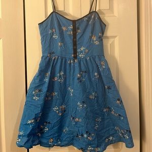 This is a short spaghetti strap blue dress with palm trees and boats all over it